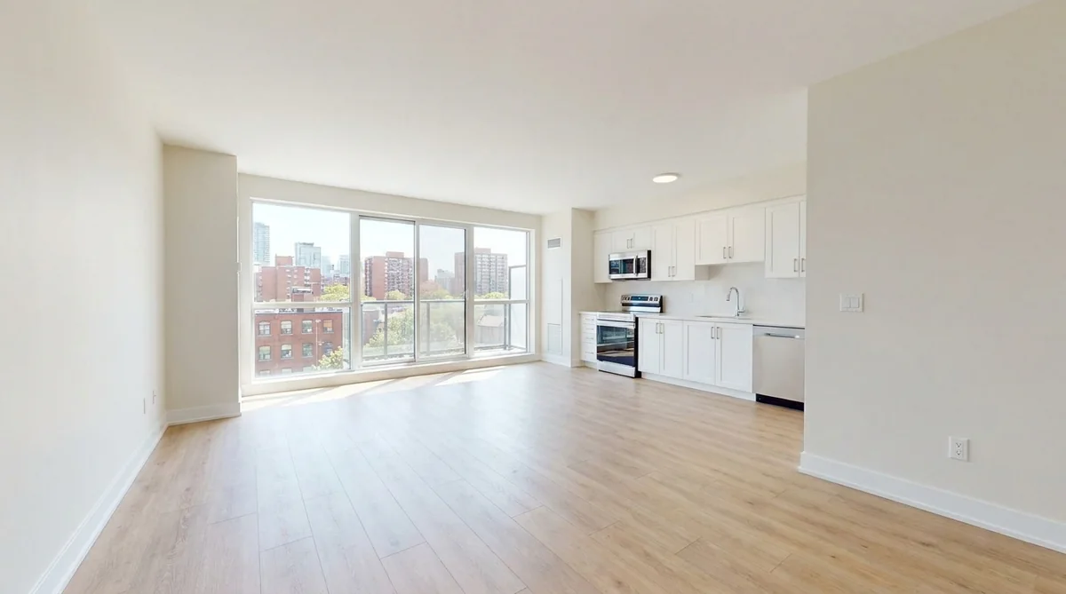 Bright empty newly renovated Toronto rental apartment with white kitchen, oak floors and a city view, ready to rent